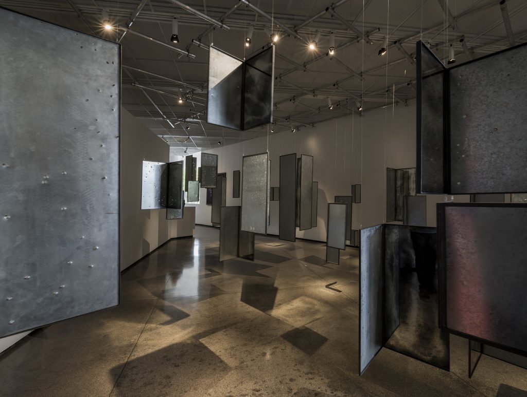 Instalação O tempo é, de Carolina Cordeiro, com painéis escuros suspensos pela galeria no Panorama da Arte Brasileira.